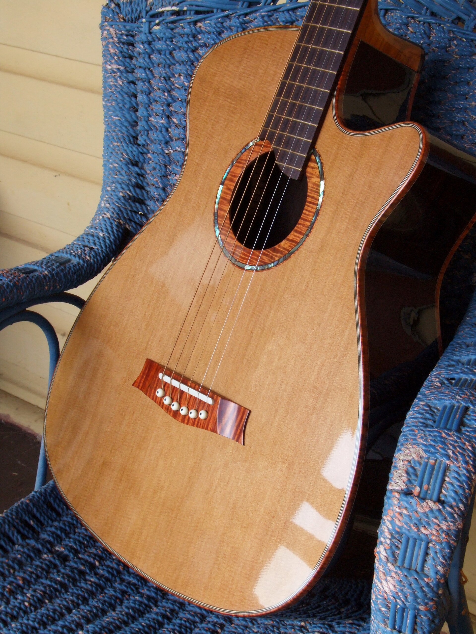 Cedar and rosewood steel string guitar sat on a blue wicker chair