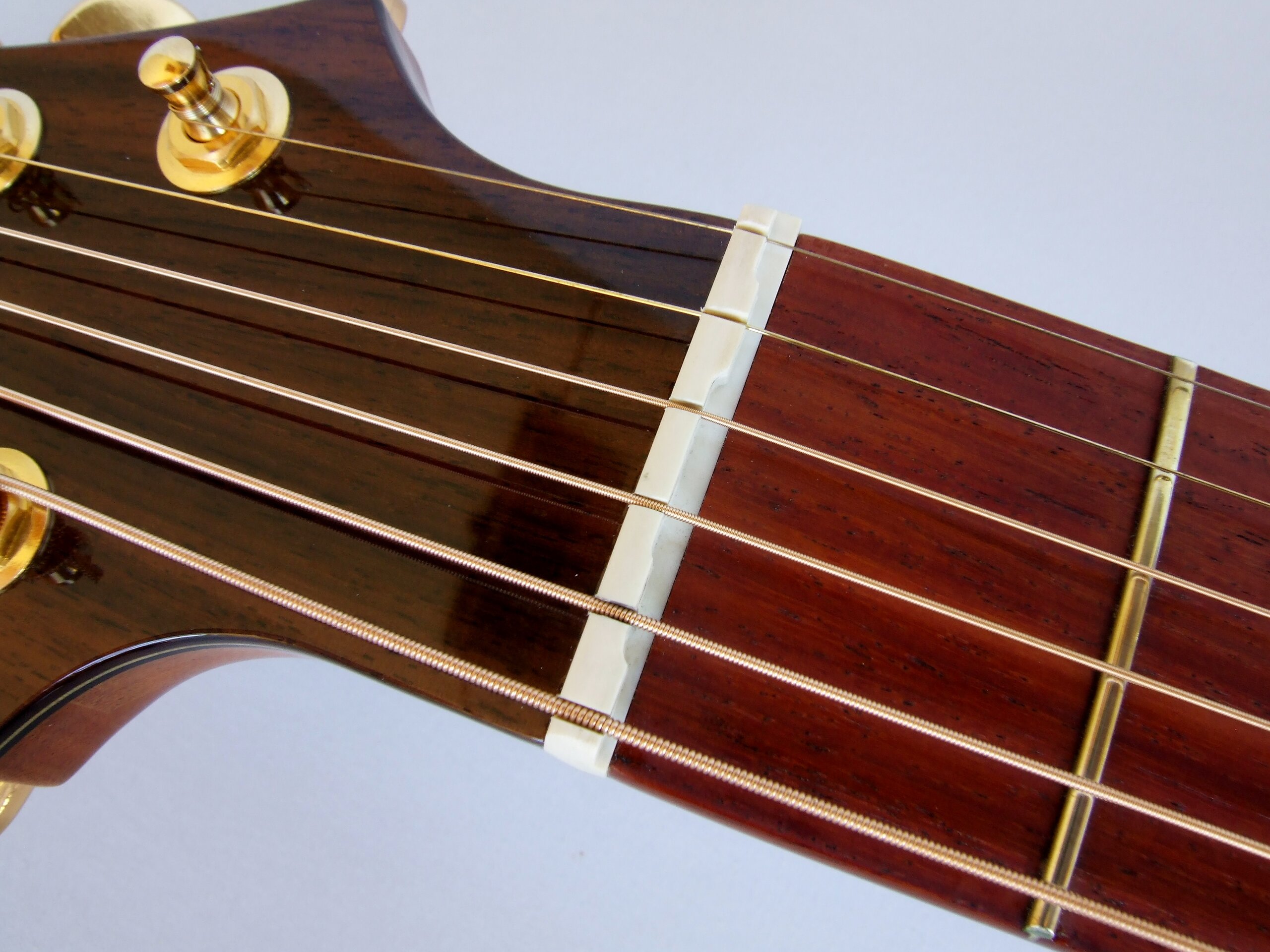 Detail of compensated nut on a steel string guitar