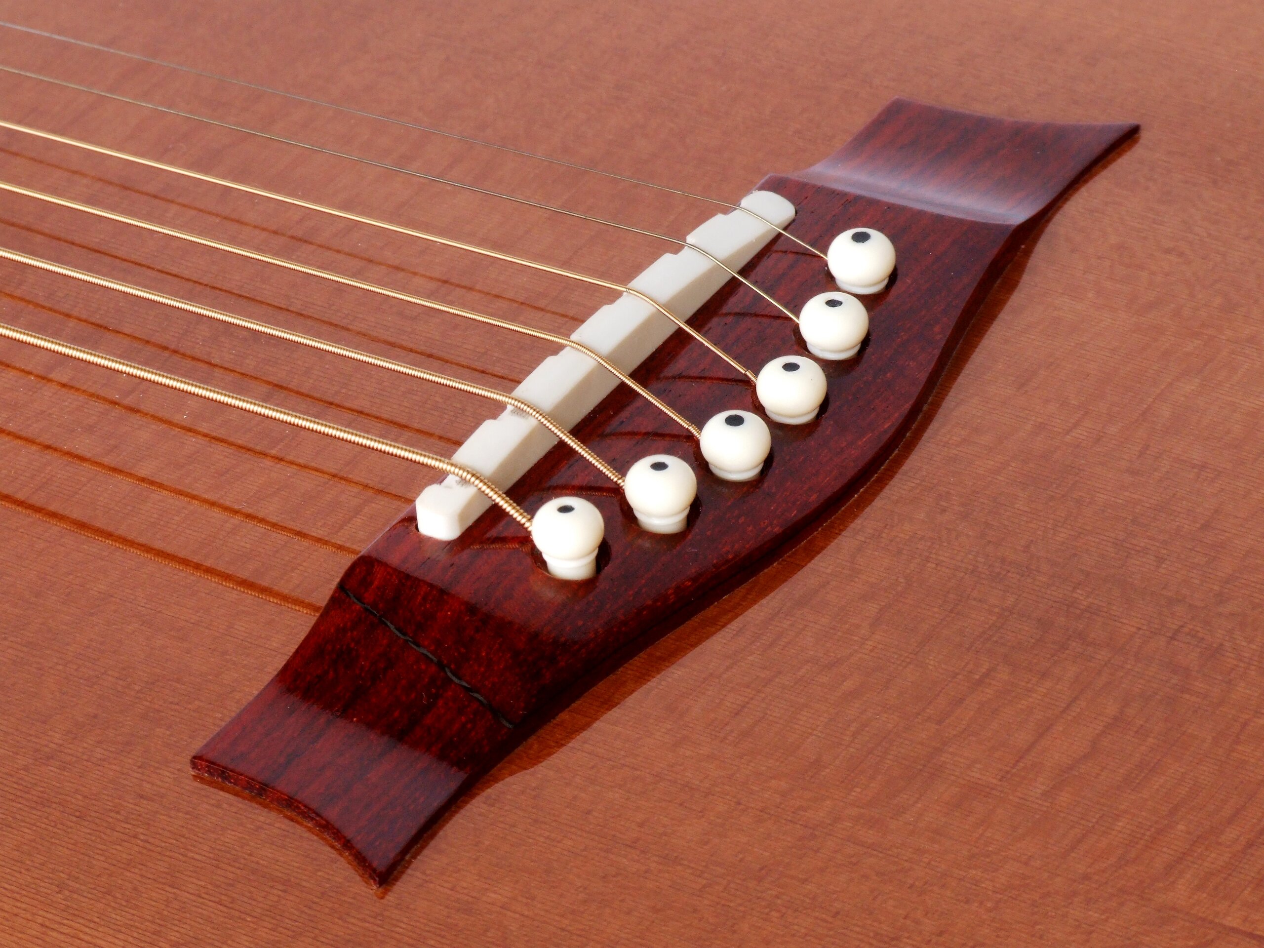 Carbon fibre reinforced bridge on a steel string guitar with a redwood top