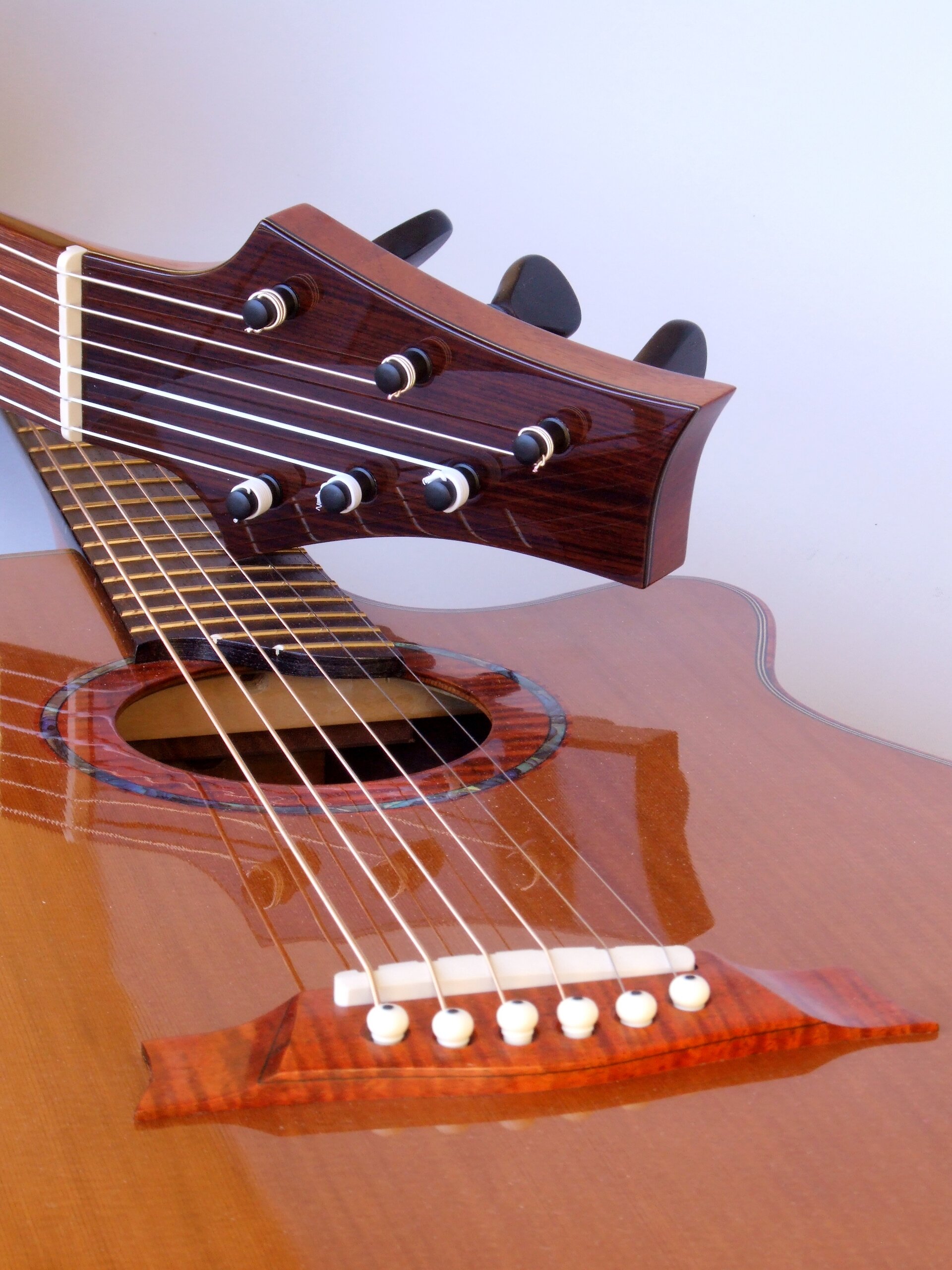 Classical guitar headstock resting on a steel string guitar