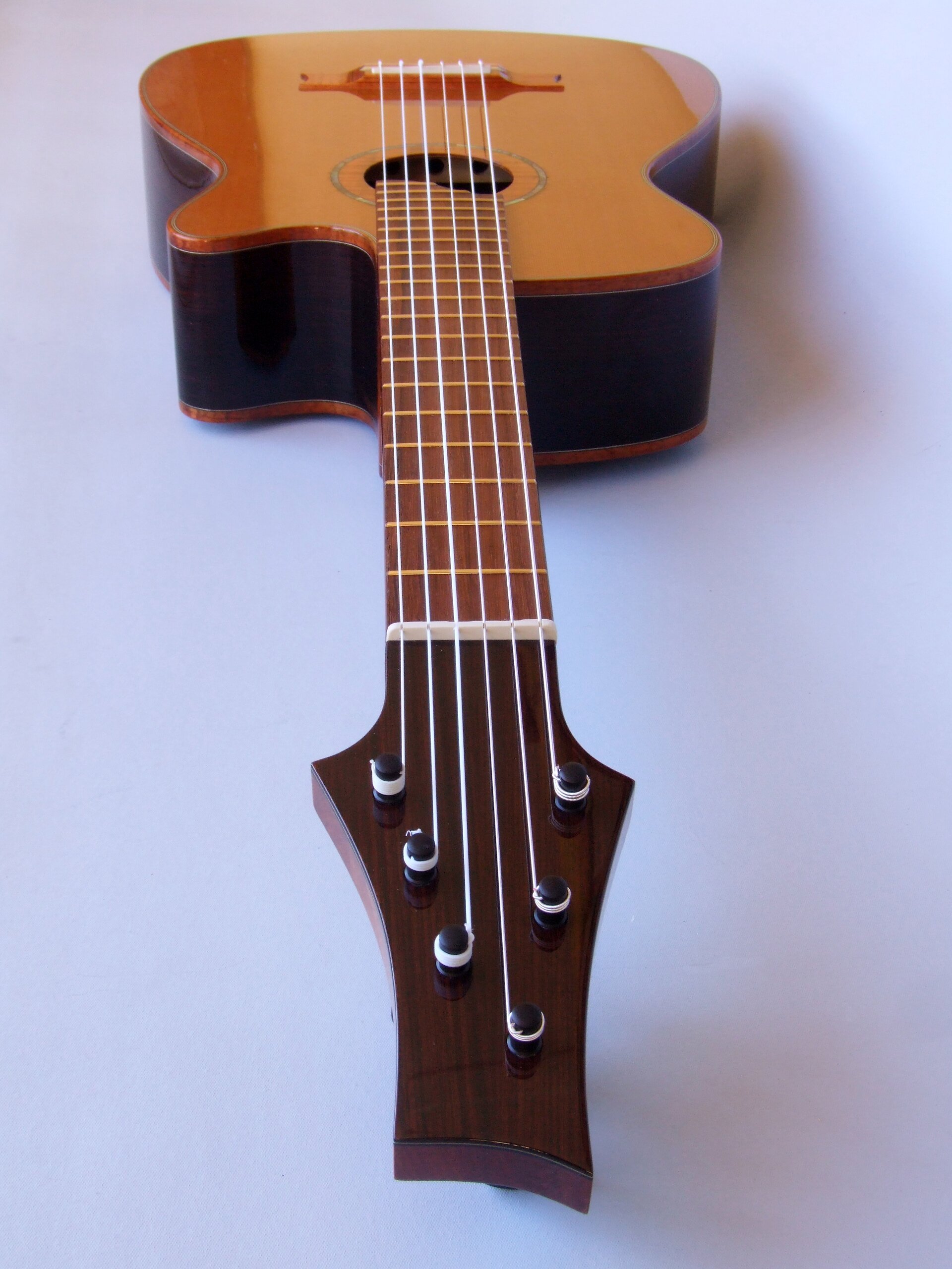 Looking down the neck of a cedar topped cutaway classical guitar with planetary peg tuners