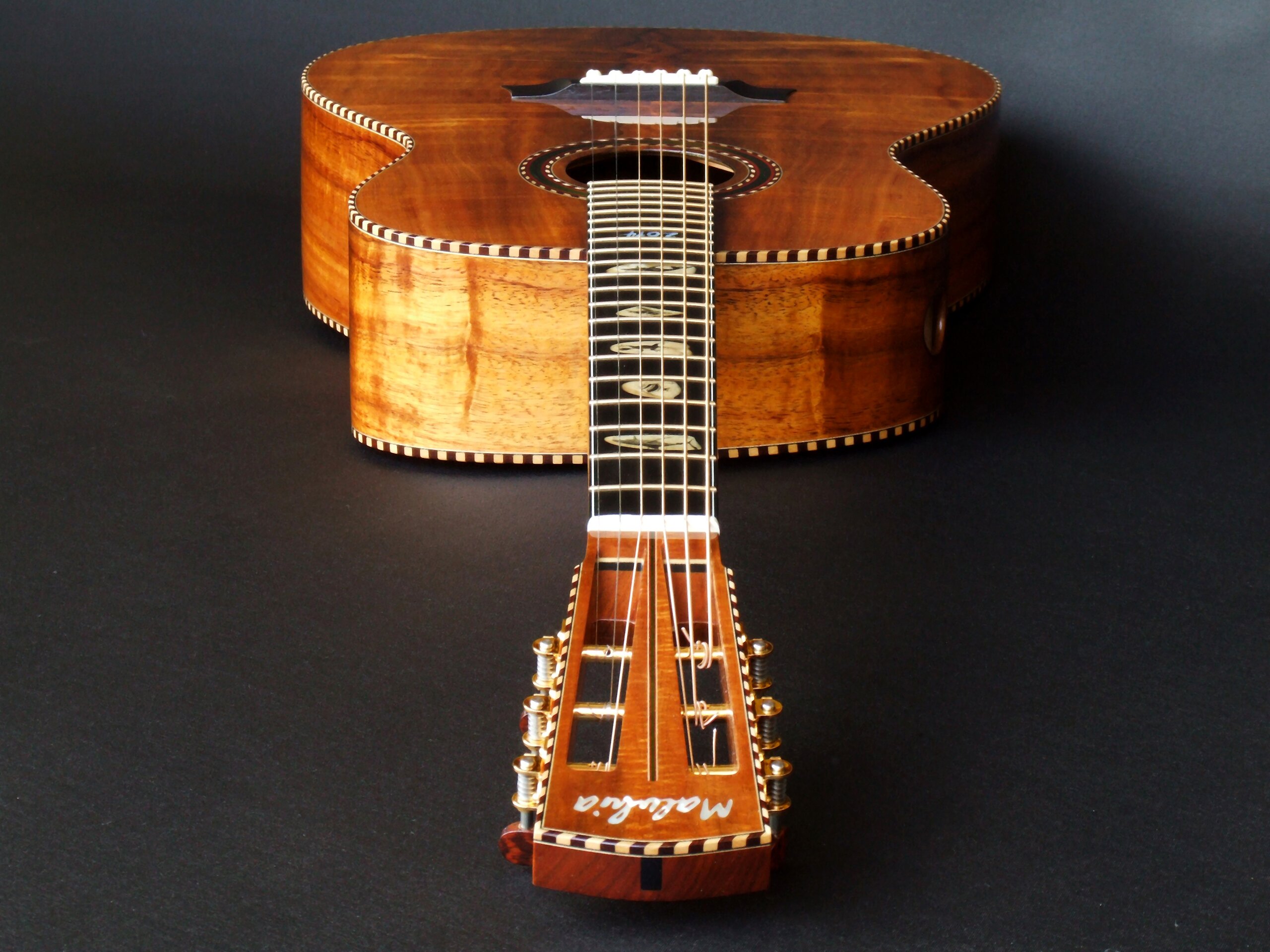 Looking down the neck of a figured koa wedge bodied guitar by Trevor Gore